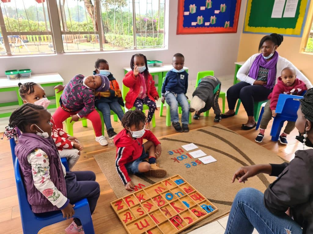 Young children learning phonics together in a circle with their teacher