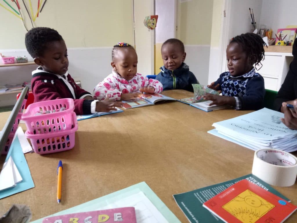Children reading picture books together at a table