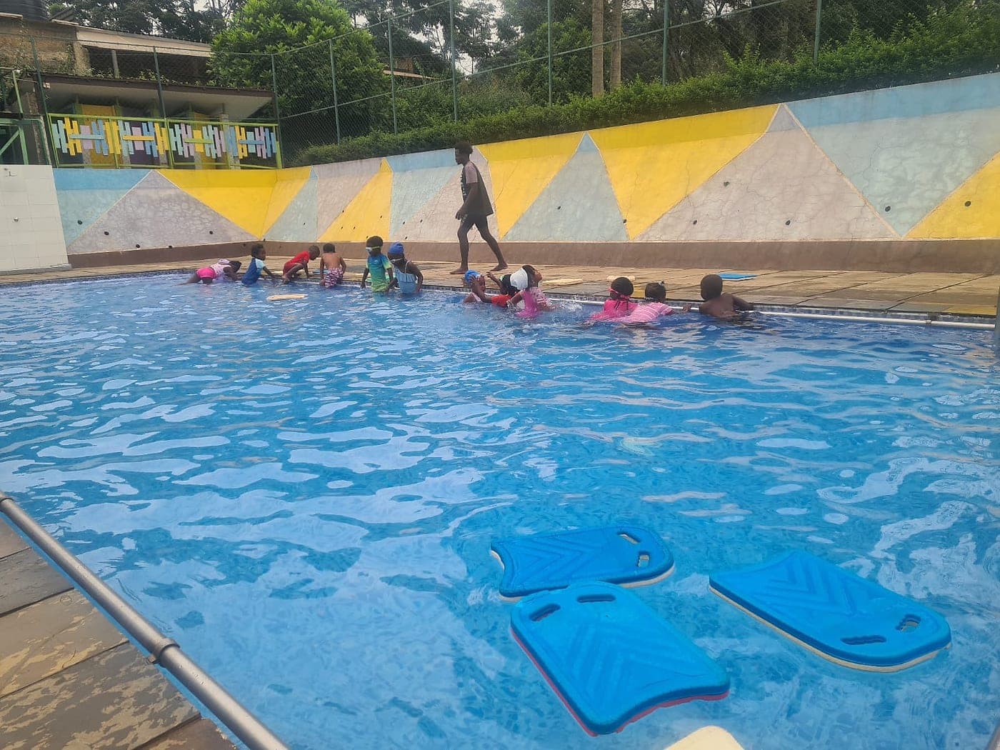 Children at a swimming lesson in the school pool, kickboards floating in the foreground